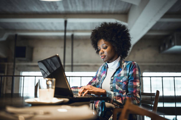 Casual woman, African-American Ethnicity, working at laptop in cafe. stock photo