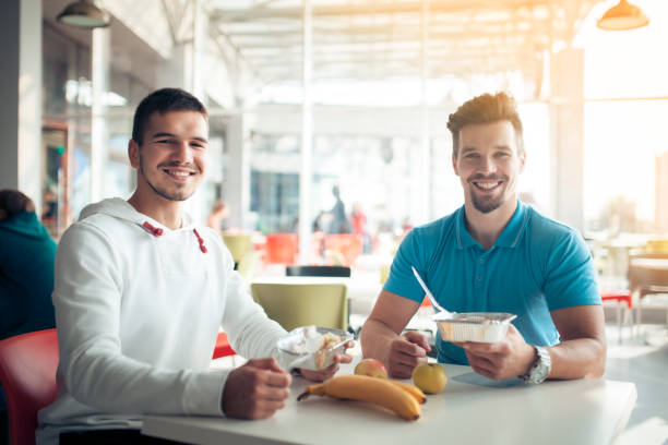 two students have dinner in cafe with healthy food;