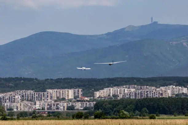 Motorless sailplane towed by another aircraft over a city