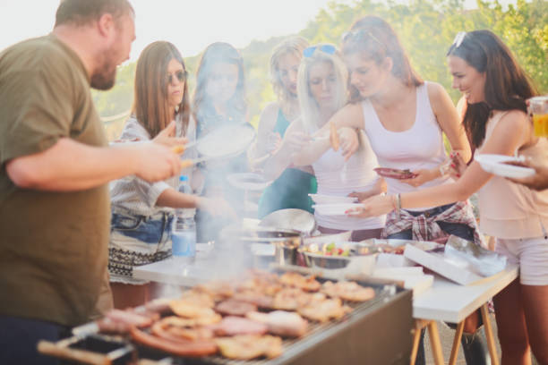istock Group of people standing around grill 987408814