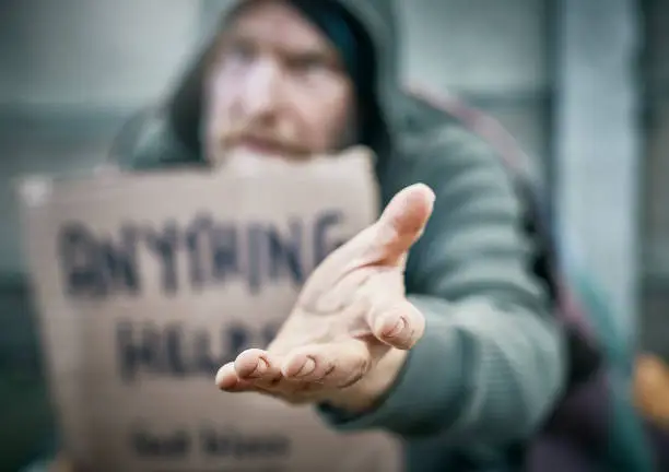 Photo of Beggar in street stretches out hand for donation