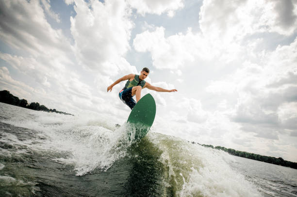 istock Young attractive man riding on the green wakeboard 987442194