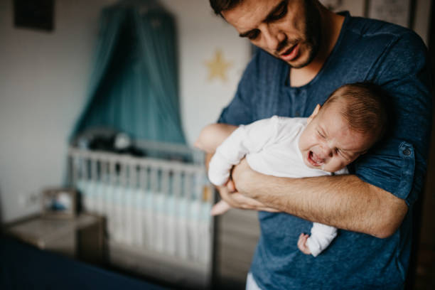 Dad Holding crying baby in the colic carry Dad Holding crying baby in the colic carry crying stock pictures, royalty-free photos & images