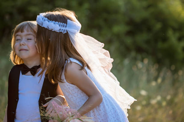 Groom is kneeling in front his wife and daughter and giving to them a wedding bouquet after the ceremony.