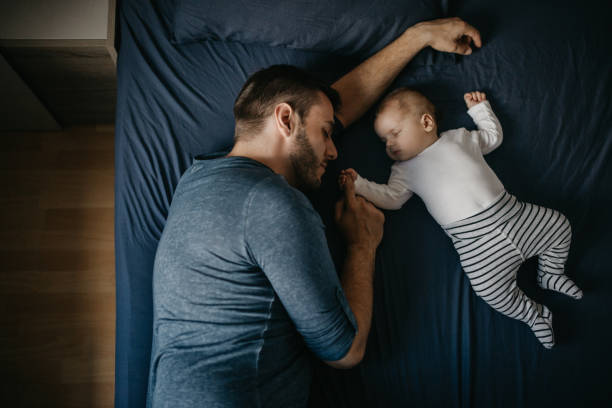 garçon nouveau-né dort avec son père sur le lit - baby sleeping bed babies only photos et images de collection