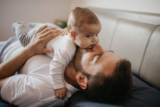 padre che gioca a letto con il suo bambino - clothing love family with one child parent foto e immagini stock