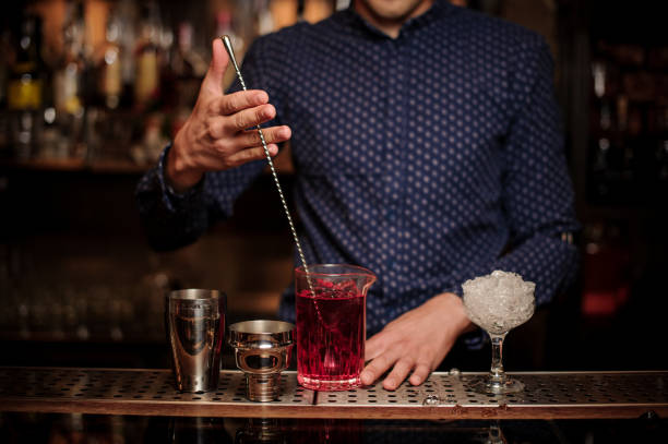 istock Bartender stirring a sweet and fresh pink summer cocktail 987462528