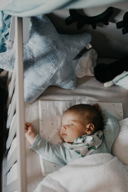 piccolo bambino carino che dorme in nursery cot - baby sleeping bedding teddy bear foto e immagini stock