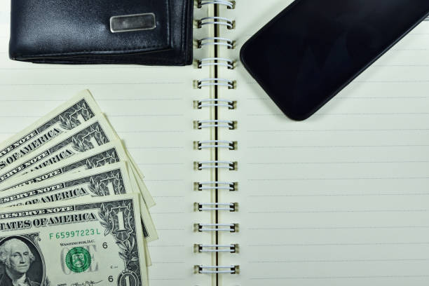 istock top view of dollar smartphone and pocket bag on notebook 987469740