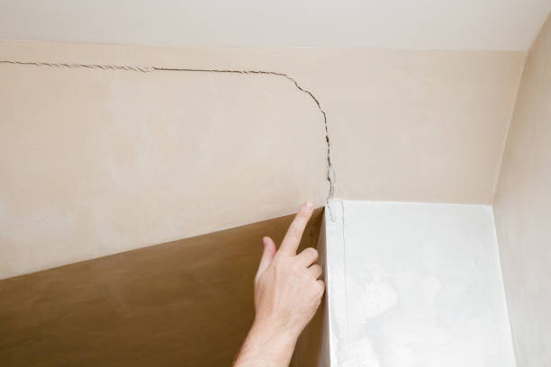 man's hand finger pointing to the cracked wall in house. building problems and solutions concept. - quality control examining house residential structure imagens e fotografias de stock