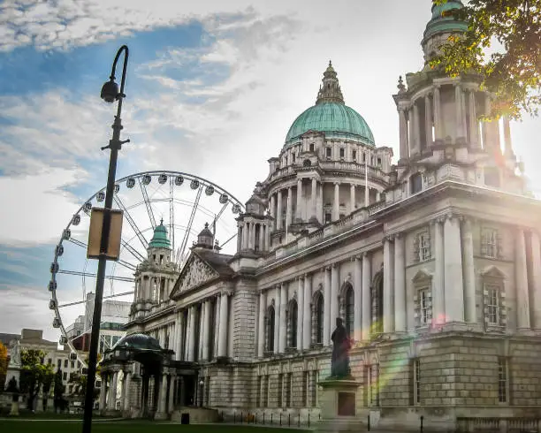 Photo of Belfast City Hall in Northern Ireland with sun flare and ferris wheel in the background