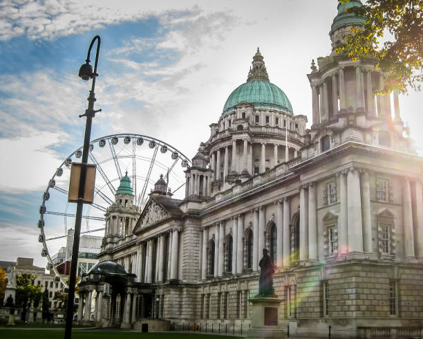 prefeitura de belfast, na irlanda do norte com o clarão do sol e da roda gigante no fundo - ferris wheel - fotografias e filmes do acervo