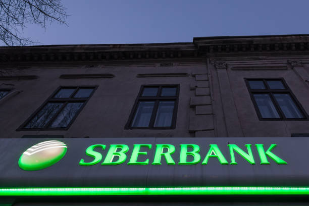 sberbank logo allumé sur une filiale de belgrade, au cours de la soirée. sberbank est l’une des plus grandes banques de russie, présente dans les balkans - lighting equipment office building night city photos et images de collection