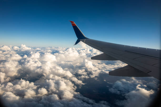 istock An airplane wing through airplane window with blue sky background 987539398