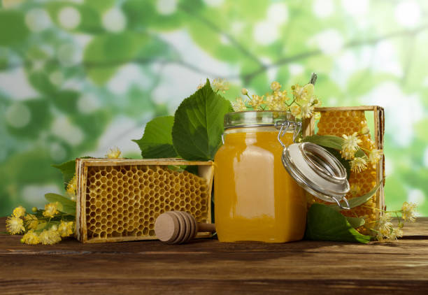 istock Honey in jar with lid, honeycomb on table, close-up 987545468