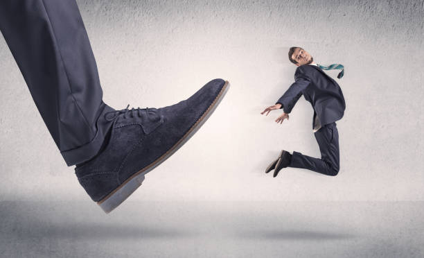 istock Small businessman kicked by big shoe 987553806
