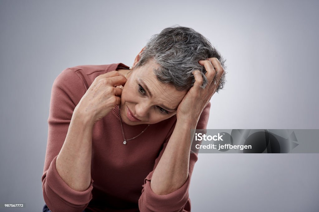 How will I know if I'm right? Studio shot of a mature woman looking stressed out against a gray background Anxiety Stock Photo