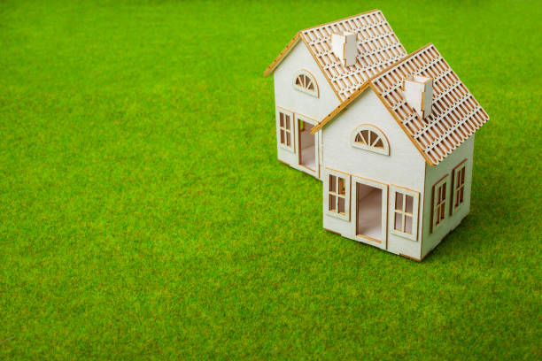istock Houses Arranged In Row On Grassy Field 987573604