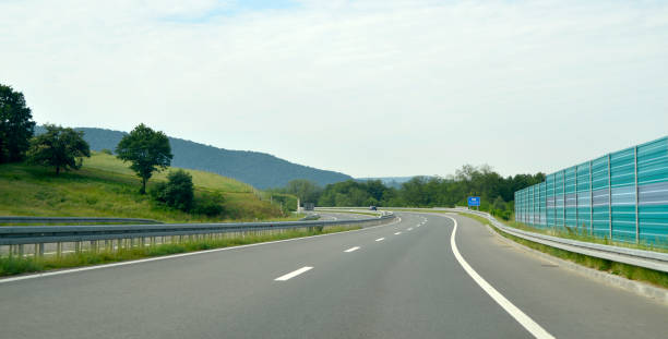 bend to the left on the new, modern, multiple lane highway, with a protective fence - multiple lane highway highway car field imagens e fotografias de stock