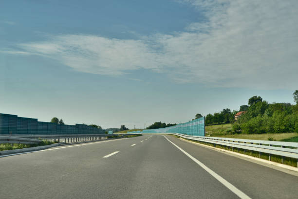 dobre à esquerda sobre o novo, moderno, estrada de pistas múltiplas, com uma vedação protetora - multiple lane highway highway car field - fotografias e filmes do acervo