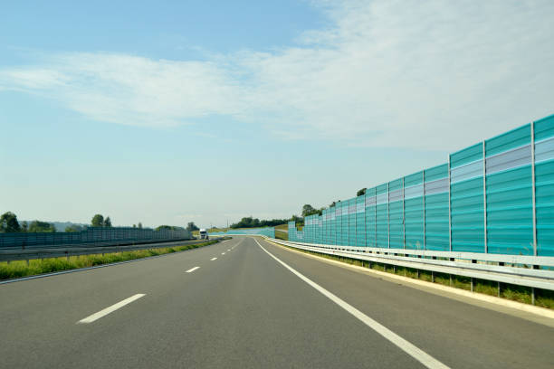 dobre à esquerda sobre o novo, moderno, estrada de pistas múltiplas, com uma vedação protetora - multiple lane highway highway car field - fotografias e filmes do acervo