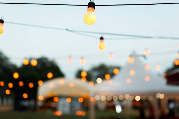 warm light bulbs at the evening event string wired with warming Light Bulbs hanging in the area of wedding events celebration in the night bohemia stock pictures, royalty-free photos & images