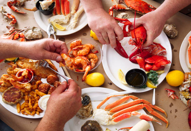 Seafood Feast Overhead view of two men eating at a seafood feast crab seafood photos stock pictures, royalty-free photos & images