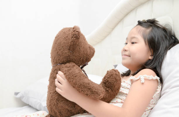 istock Cute girl is playing with a teddy bear 987606666