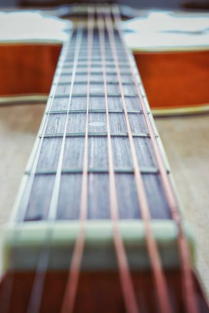 istock Acoustic guitar strings on wooden table with sunlight close up top view abstract background 987622318