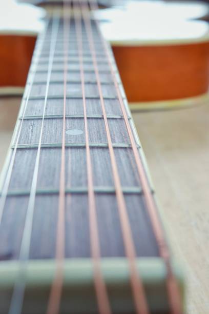 istock Acoustic guitar strings on wooden table with sunlight close up top view abstract background 987622332
