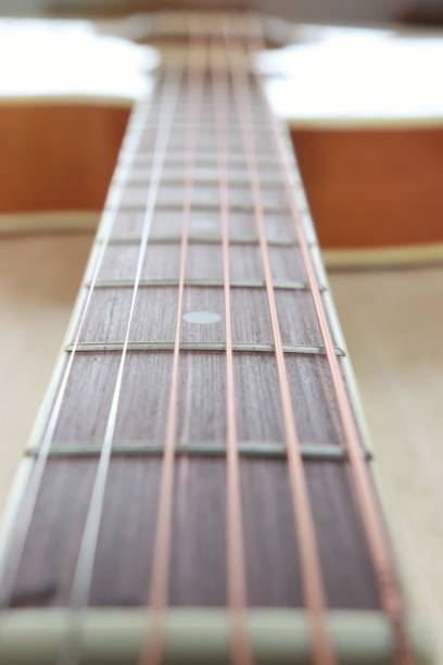 istock Acoustic guitar strings on wooden table with sunlight close up top view abstract background 987622344