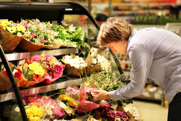 istock Man buying flowers at a garden center .Using smarthone 987627430