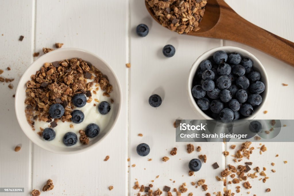 Bowl of yogurt, blueberries and cereals on a wooden spoon Breakfast with yogurt, crispy muesli and fresh blueberries Close-up Stock Photo