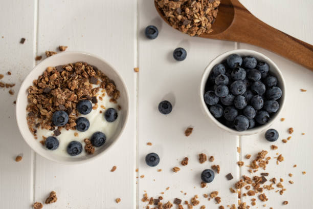 Bowl of yogurt, blueberries and cereals on a wooden spoon stock photo
