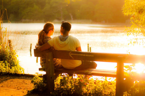 istock Couple sitting on a bench by a lake 987634442