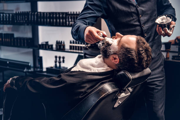 Barber applies shaving foam Barber applies shaving foam to a man's face in a saloon. saloon photos stock pictures, royalty-free photos & images