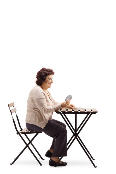 istock Elderly woman seated at a table playing cards 987648212