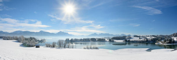 panoramic scene with lake Forggensee and mountain range in region Allgau in Bavaria at winter panoramic scene with lake Forggensee and mountain range in region Allgau in Bavaria at winter forggensee lake photos stock pictures, royalty-free photos & images
