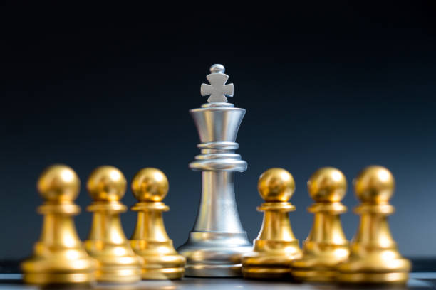 istock Silver king chess piece stand with pawn on black background 987662240