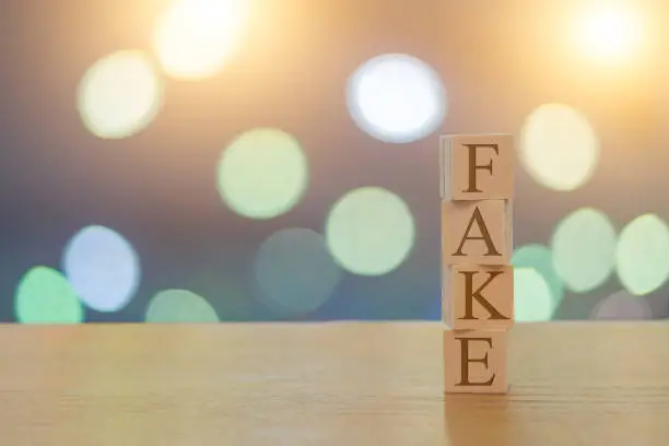 Fake message on wooden cubes on a  bokeh background