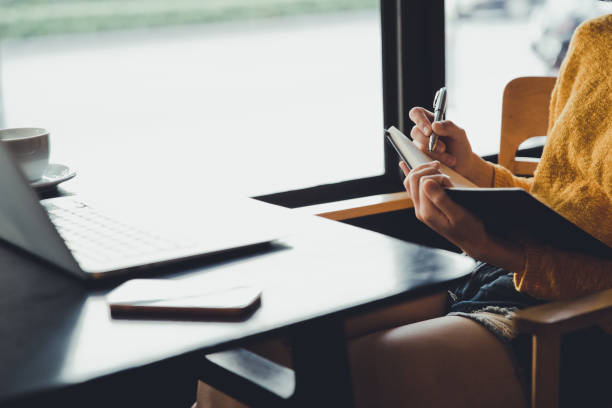 istock A hipster asian woman working with laptop and writing information into notebook 987682436