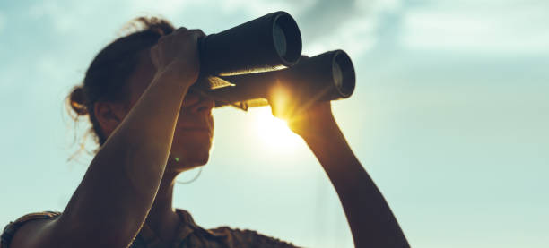 Beautiful Young Woman Looking Through Binoculars At The Sea On A Bright Sunny Day stock photo