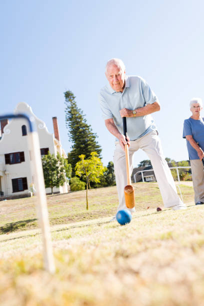 istock Focussed look of concentration as senior man holds mallet with two hands taking his shot playing croquet 987701704