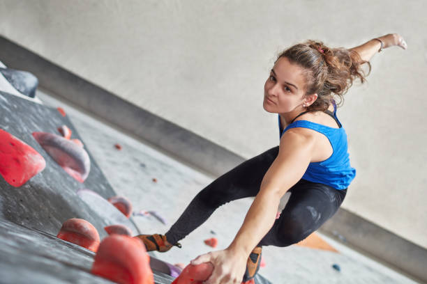 istock Determined female climbing wall in gym 987702304