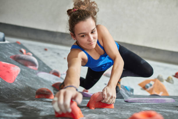istock Determined woman climbing wall in gym 987709148
