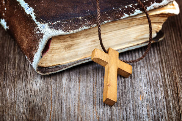istock Ancient holy book of a wooden cross on a cord. 987724340