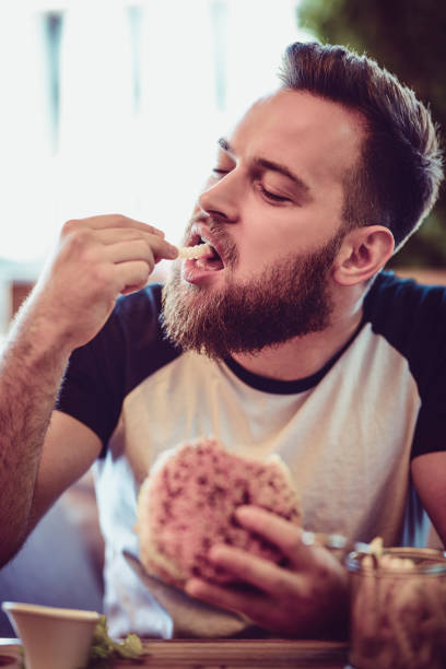 istock Handsome Male Eating A Burger In Restaurant 987733960