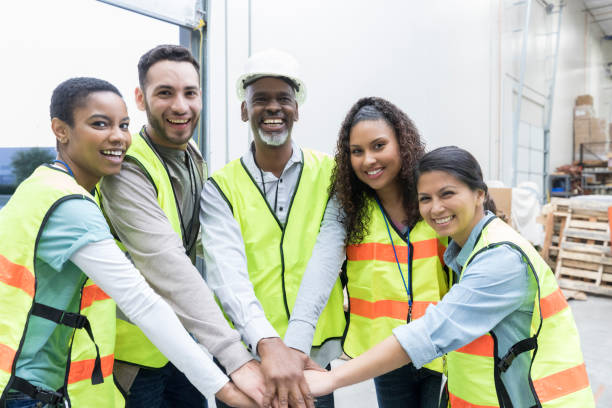 Unified distribution warehouse employees Confident diverse group of distribution warehouse employees have their hands together in unity. They are smiling at the camera. filipino ethnicity photos stock pictures, royalty-free photos & images