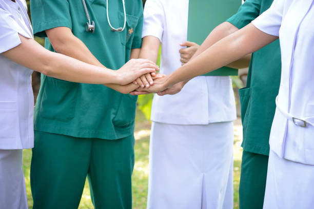 istock Doctors surgeon and nurses in a medical stacking hands. 987749786