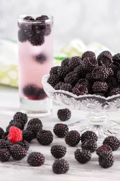 istock A cold drink with black raspberries . Vase with raspberries . Raspberry on a wooden table. 987754280